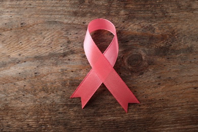 Pink ribbon on wooden background, top view. Breast cancer awareness concept