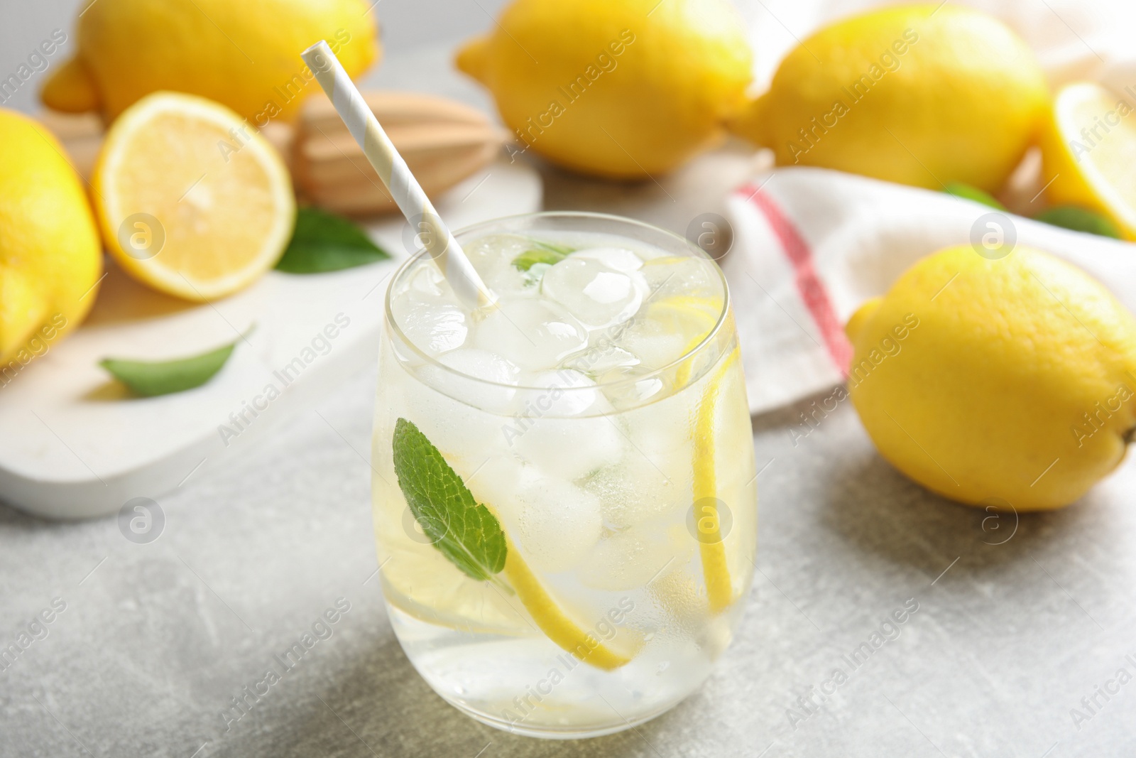 Photo of Glass of cold lemonade on light grey table, closeup