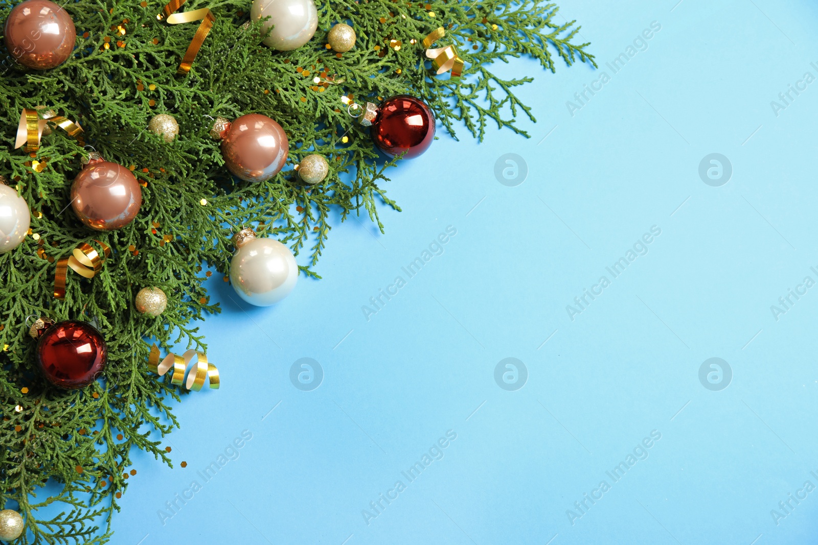 Photo of Fir tree branches with Christmas decoration on light blue background, flat lay. Space for text