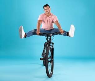 Photo of Handsome young man with modern bicycle on light blue background