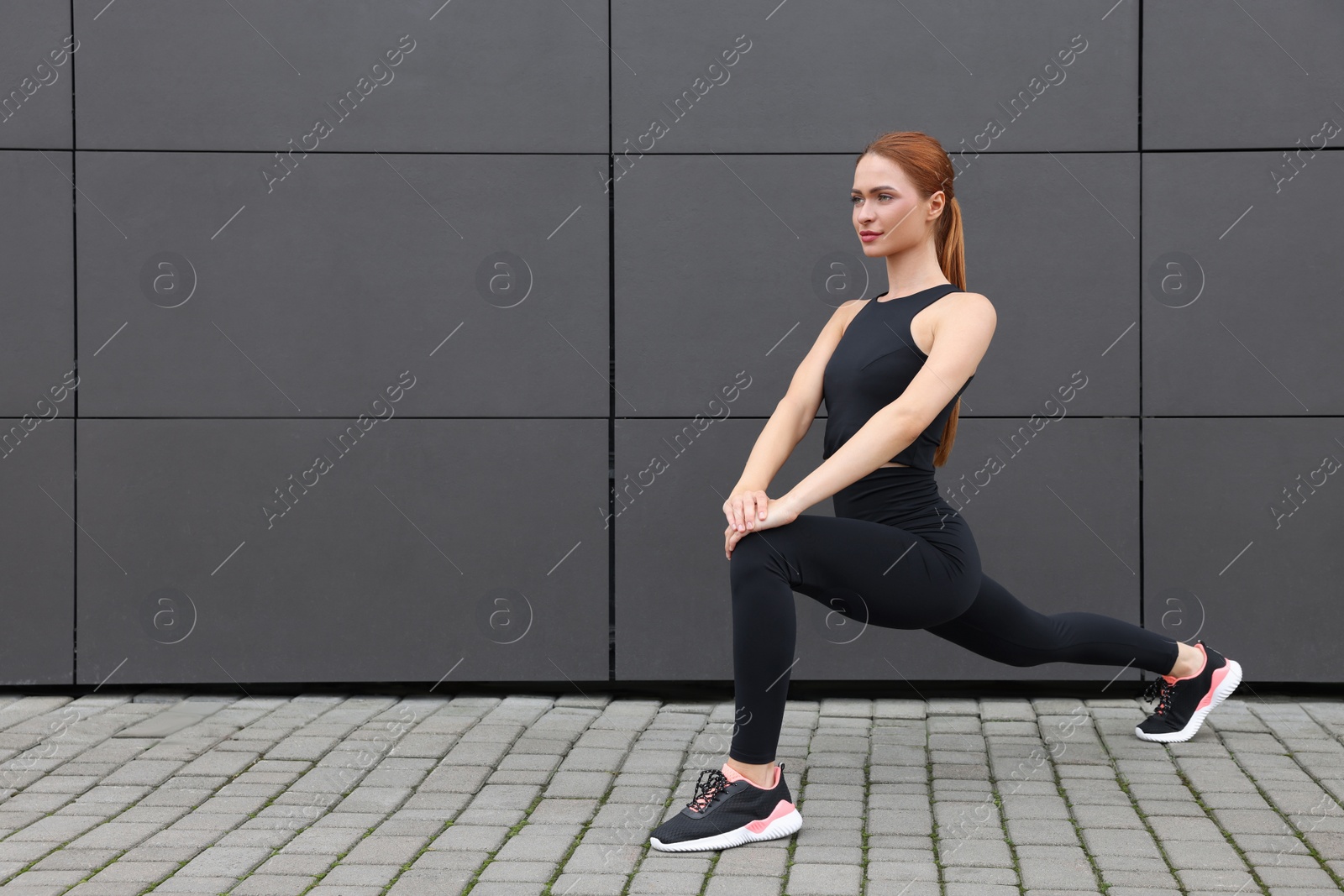 Photo of Beautiful woman in gym clothes doing exercises on street, space for text