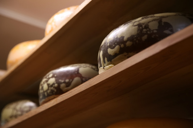 Photo of Fresh cheese heads on rack in factory warehouse, closeup