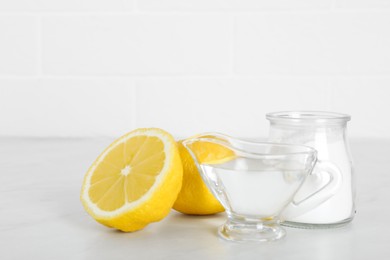Photo of Vinegar, baking soda and lemon on white marble table. Eco friendly natural detergents