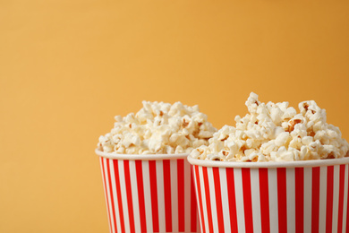 Photo of Delicious popcorn in paper cups on yellow background, closeup