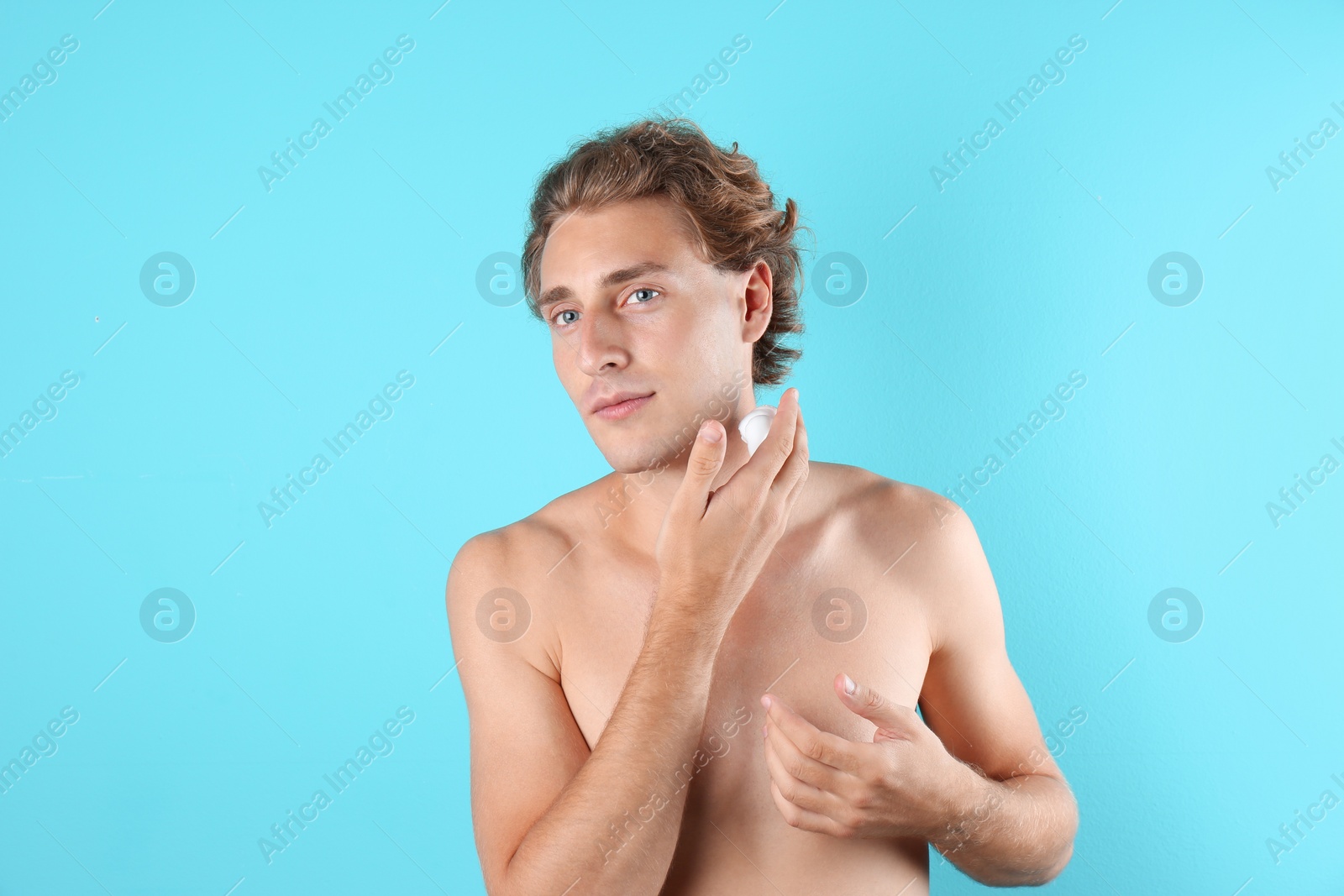 Photo of Young man applying shaving foam on color background