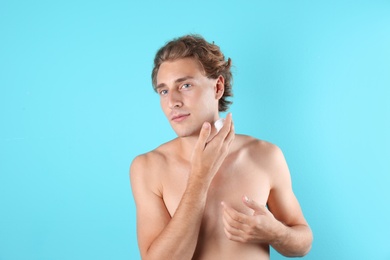 Young man applying shaving foam on color background