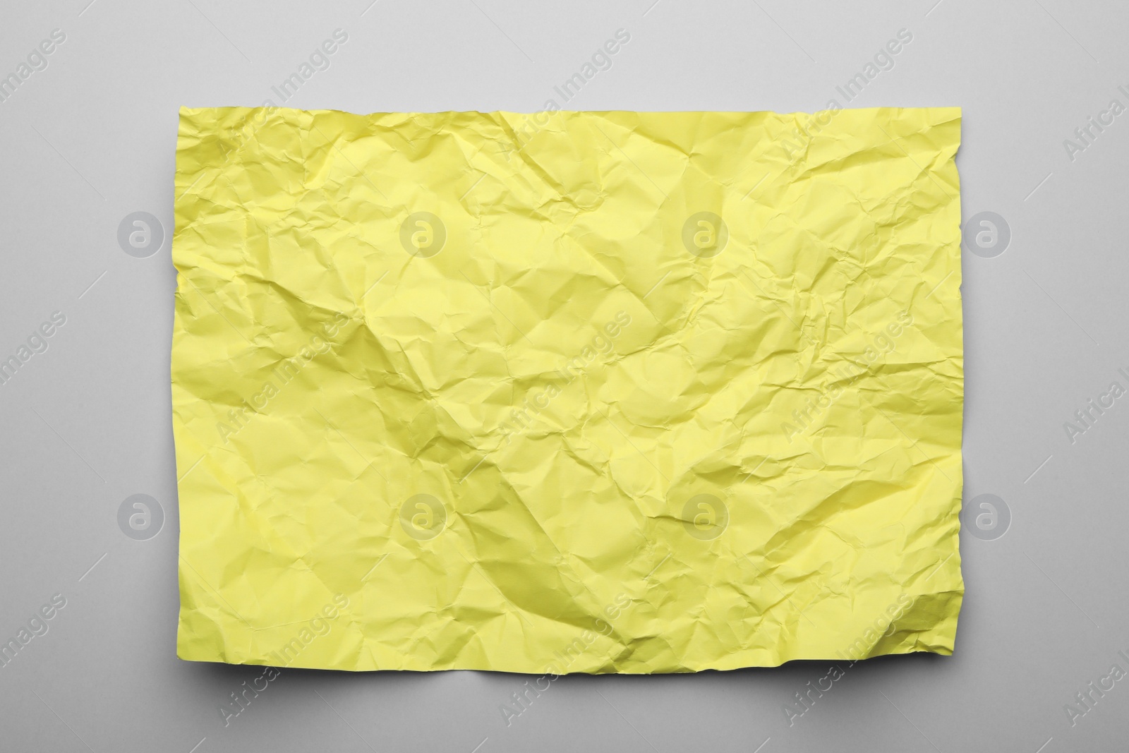 Photo of Color sheet of crumpled paper on grey background, top view