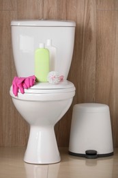 Photo of Different cleaning supplies on toilet bowl indoors