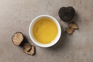 Fresh truffles and oil in bowl on light grey table, flat lay