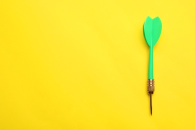 Photo of Green dart arrow on yellow background, top view with space for text