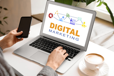 Image of Digital marketing concept. Woman using modern laptop and phone at table