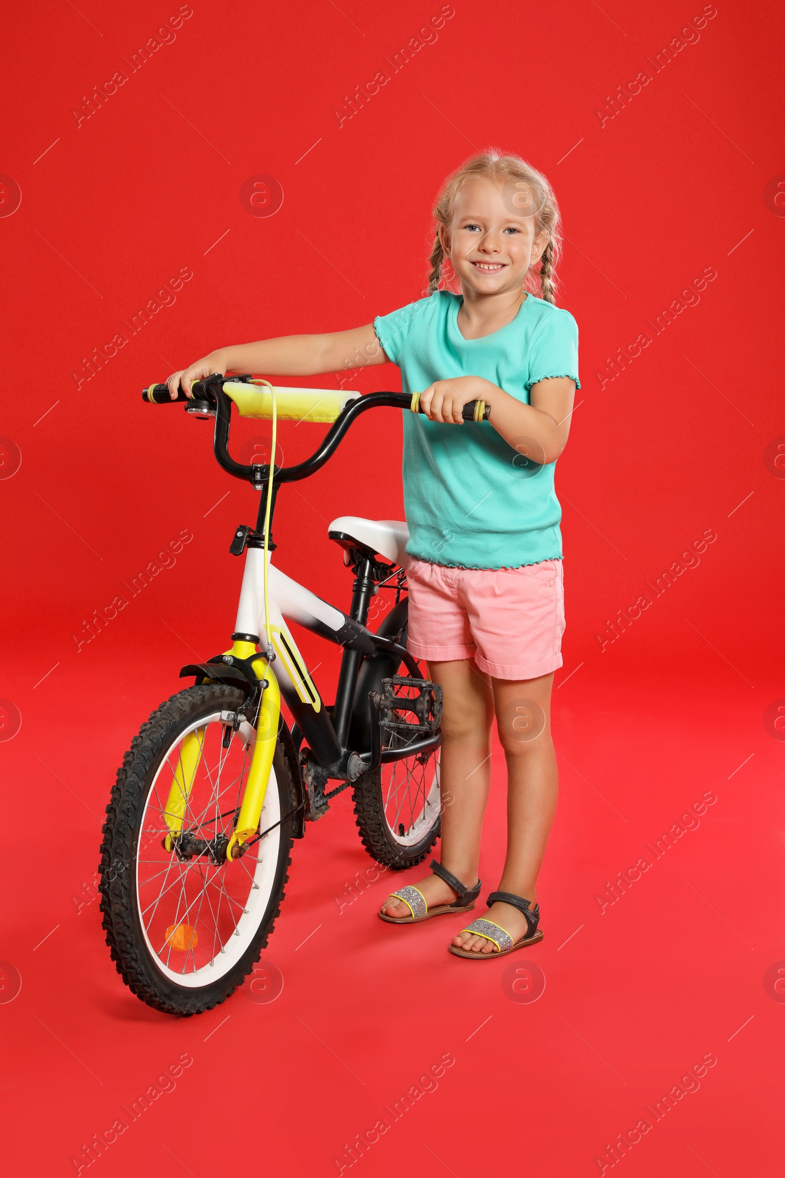 Photo of Cute little girl with bicycle on red background