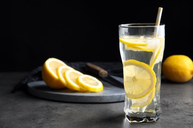 Photo of Soda water with lemon slices and ice cubes on grey table. Space for text