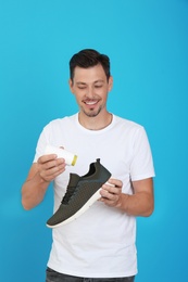 Photo of Man putting powder freshener into shoe on color background