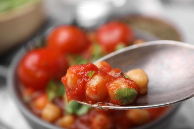 Photo of Spoon with delicious chickpea curry, closeup view