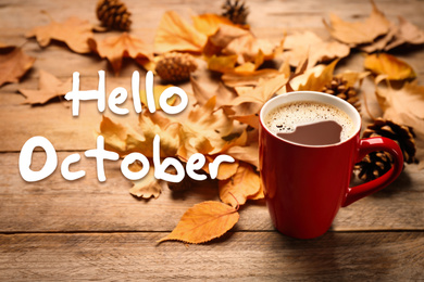 Hello October card. Cup of hot drink and autumn leaves on wooden table