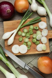 Different kinds of onions on wooden table, flat lay