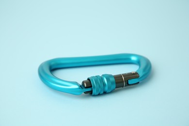 Photo of One carabiner on light blue background, closeup