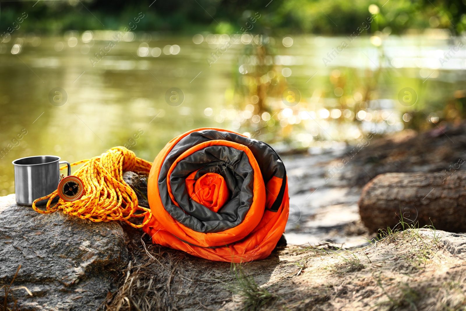 Photo of Rolled sleeping bag and other camping gear near lake