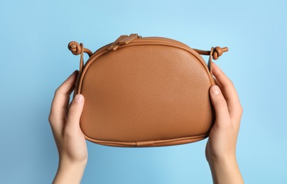 Photo of Woman holding stylish bag on light blue background, closeup