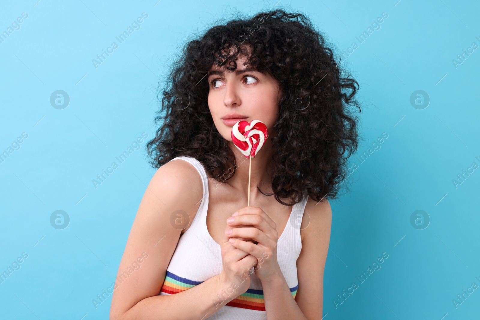 Photo of Beautiful woman with lollipop on light blue background