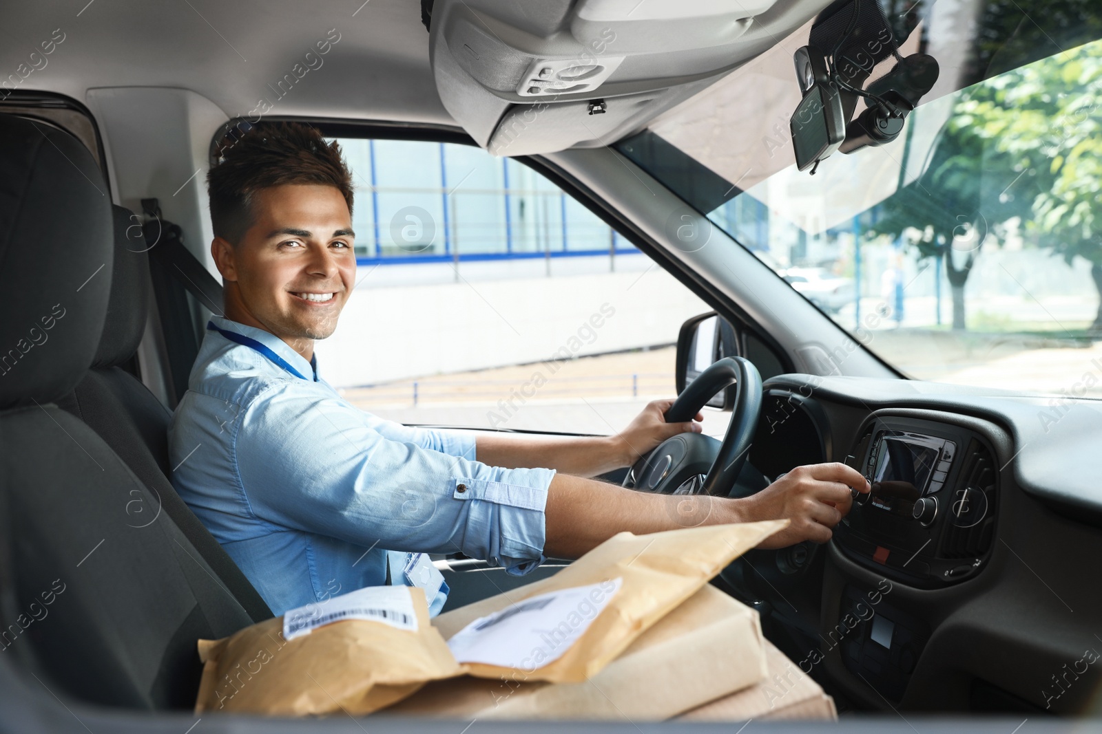 Photo of Young courier with parcels in delivery car