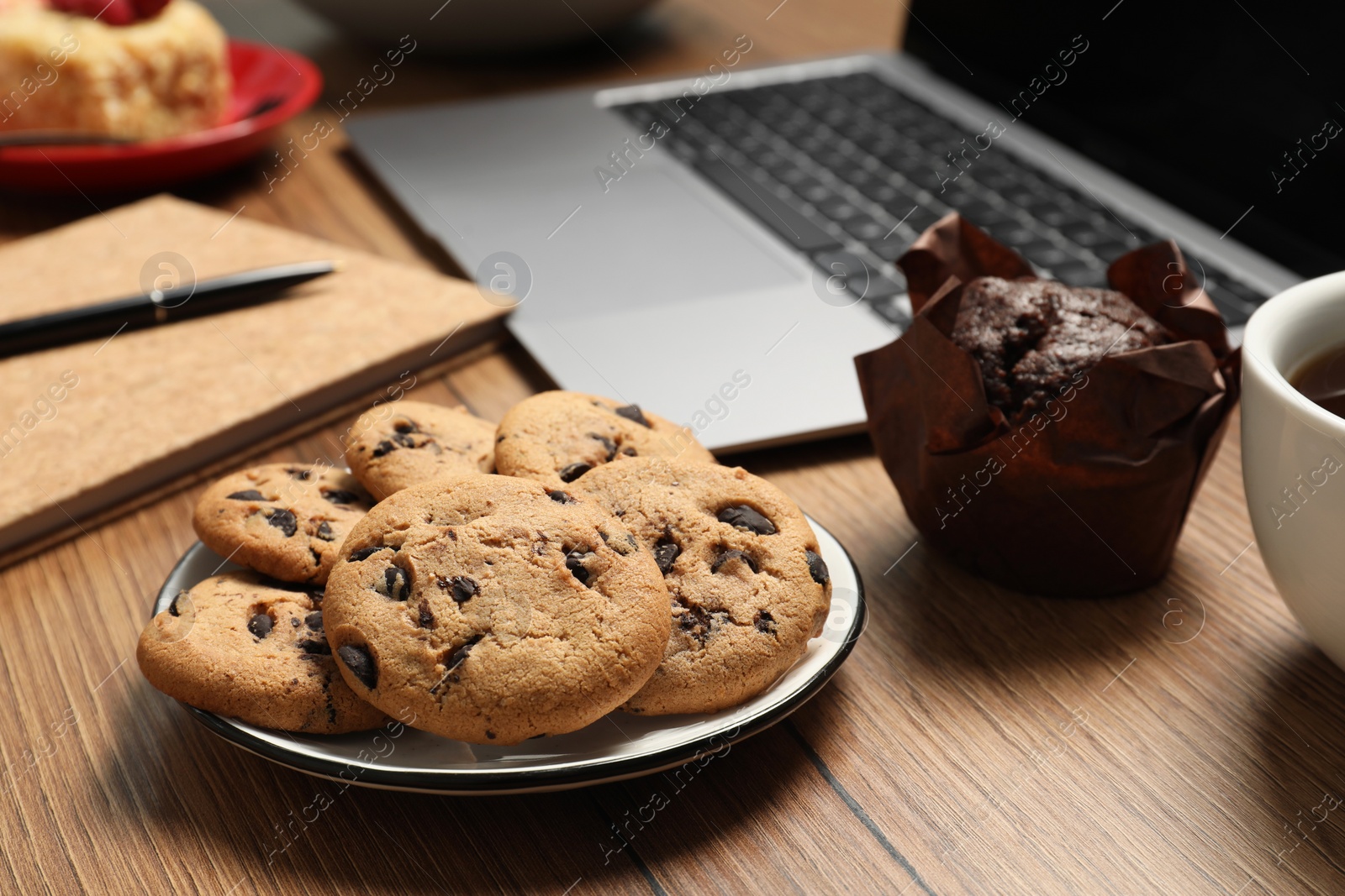 Photo of Bad eating habits at workplace. Different snacks on wooden table