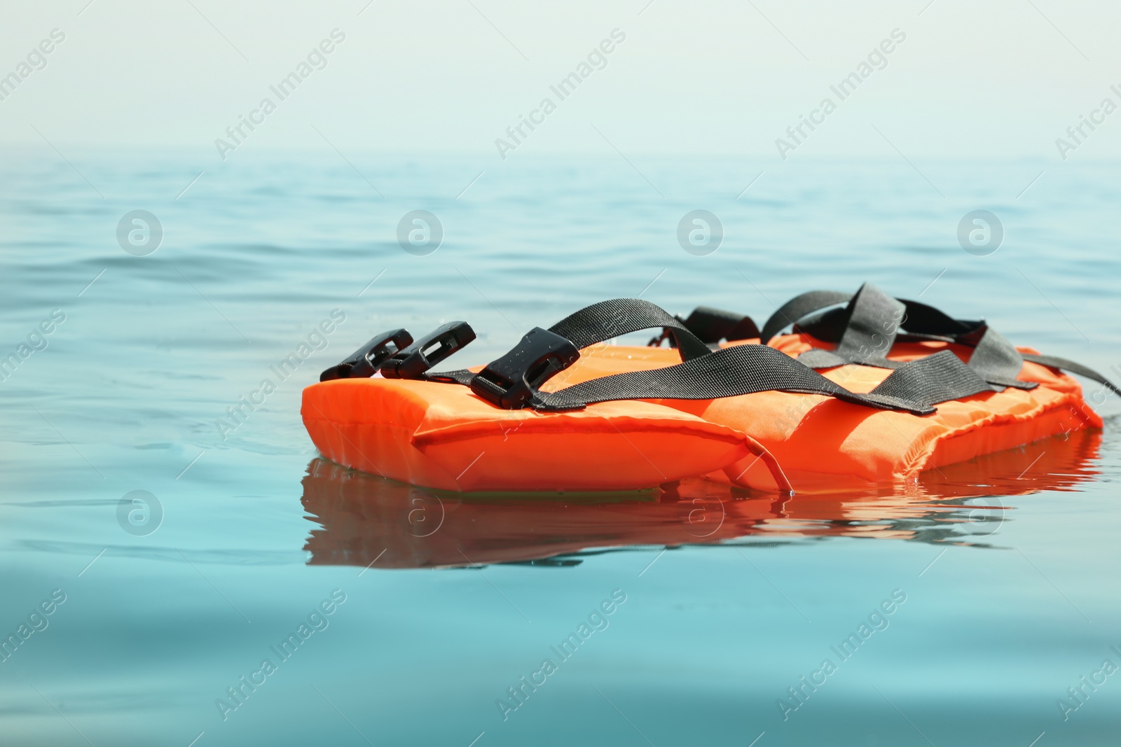 Photo of Orange life jacket floating in sea. Emergency rescue equipment