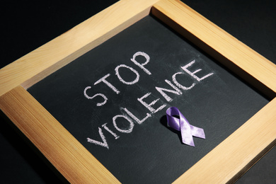 Chalkboard with purple ribbon and phrase STOP VIOLENCE on black background