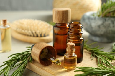 Essential oils in bottles and rosemary on table, closeup