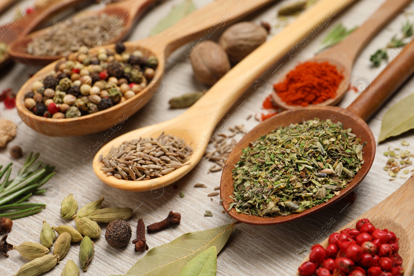 Photo of Different natural spices and herbs on light wooden table, closeup