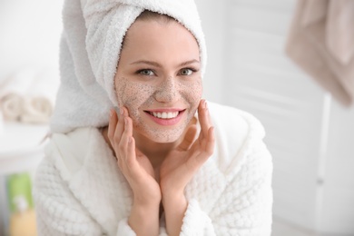 Woman with scrub on face in bathroom