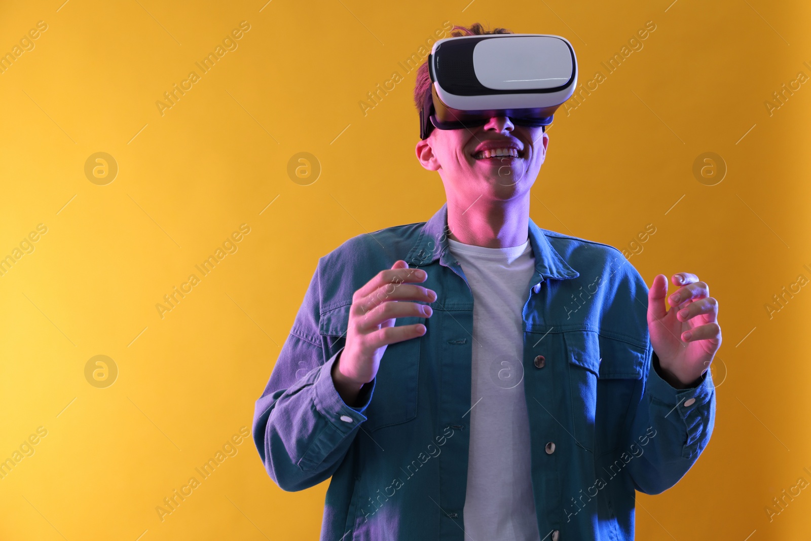 Photo of Young man with virtual reality headset on yellow background. Space for text