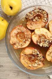 Delicious baked quinces with nuts in bowl and fresh fruits on wooden table, flat lay