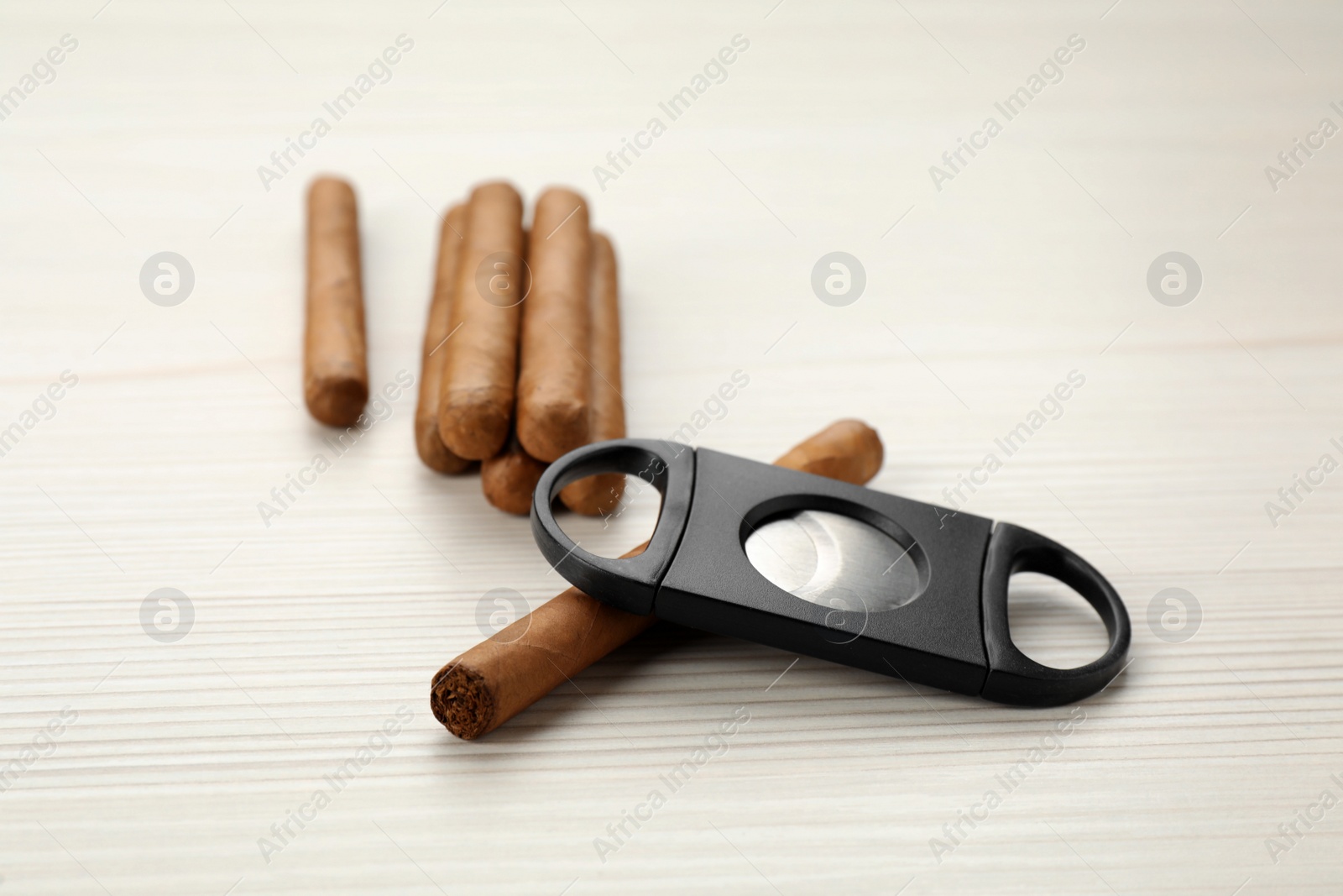 Photo of Cigars and guillotine cutter on white wooden table