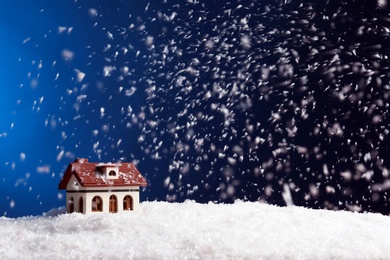 Decorative house in snowdrift on color background, space for text. Winter weather