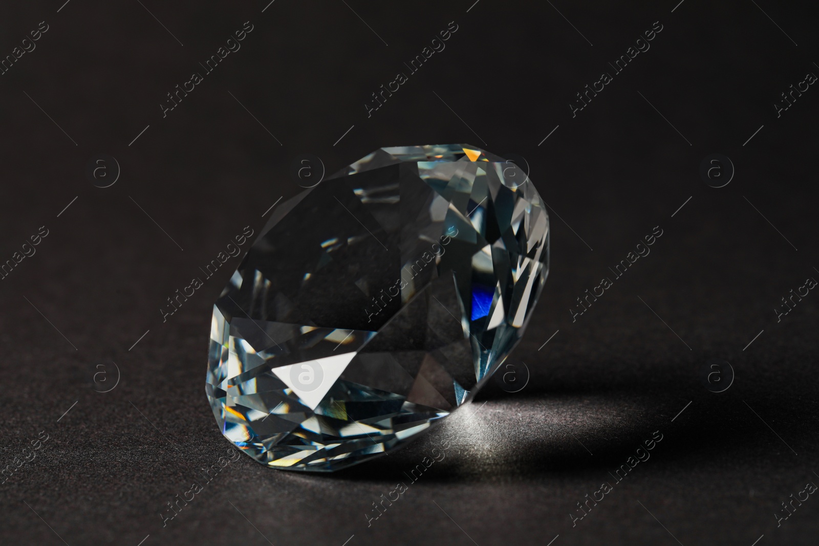 Photo of Beautiful dazzling diamond on dark background, closeup. Precious gemstone