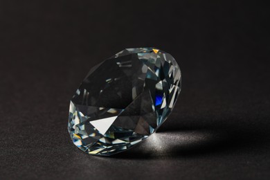 Photo of Beautiful dazzling diamond on dark background, closeup. Precious gemstone