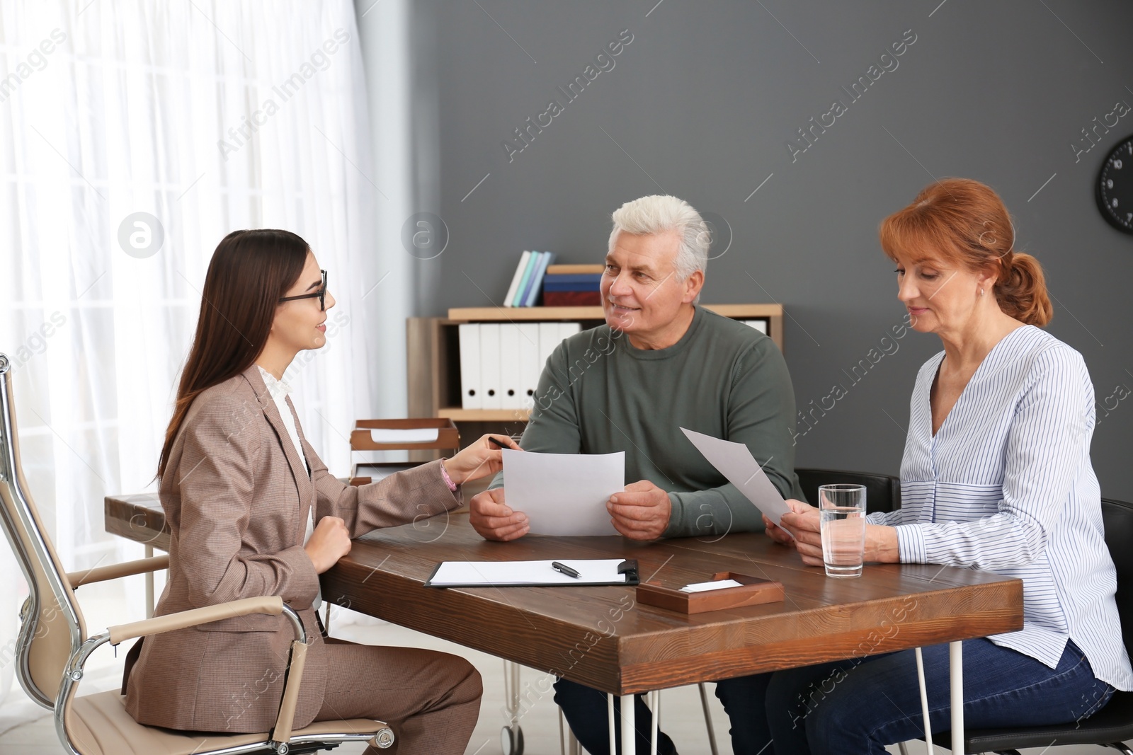 Photo of Young lawyer consulting senior couple in office