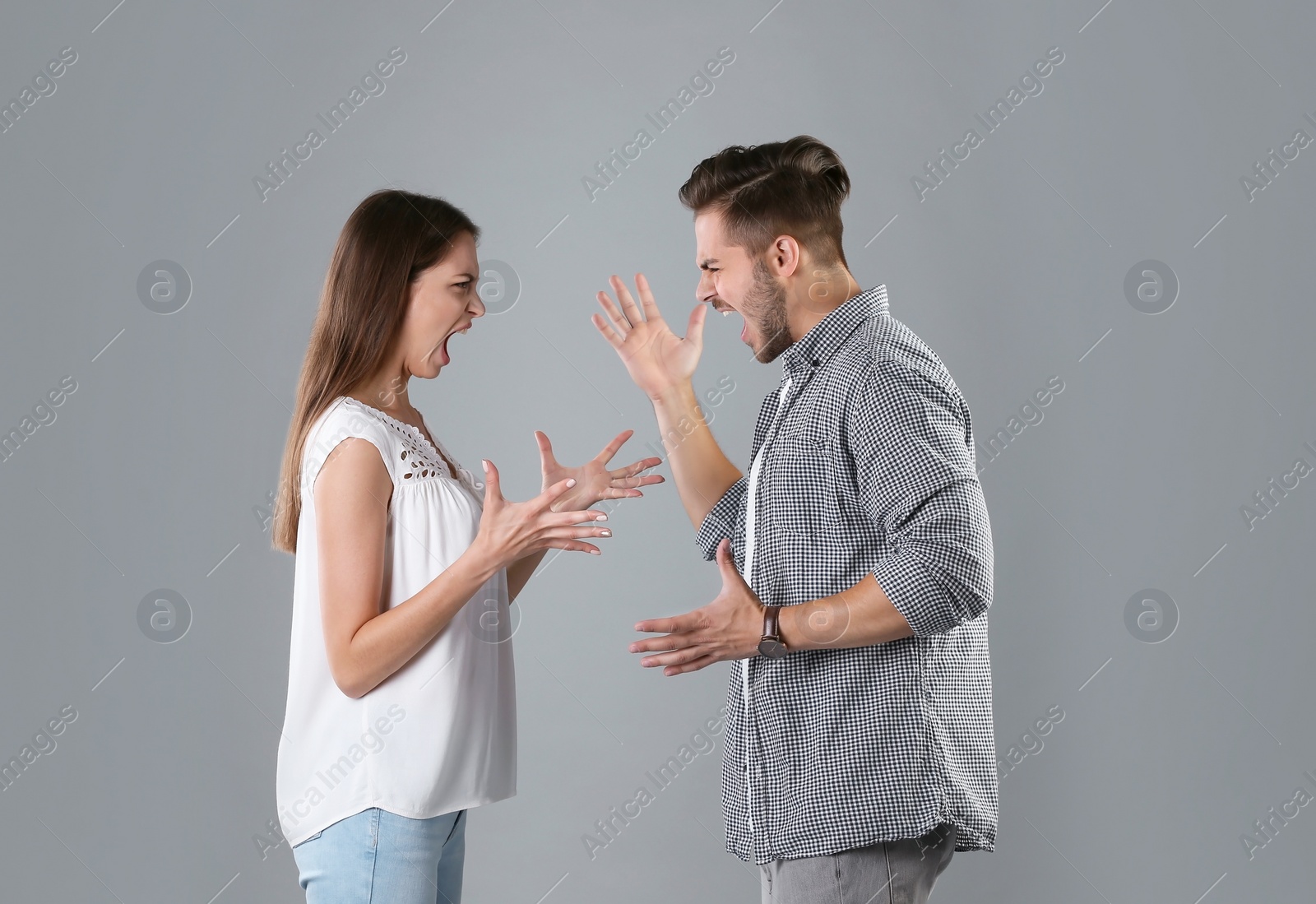 Photo of Young couple having argument on grey background. Relationship problems