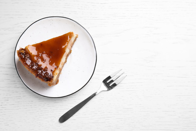 Photo of Piece of delicious cake with caramel on white wooden table, flat lay. Space for text