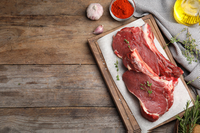 Flat lay composition with fresh beef cut on wooden table. Space for text