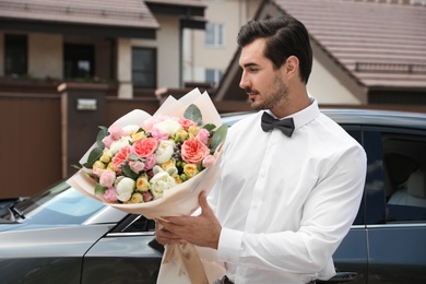 Photo of Young handsome man with beautiful flower bouquet near car outdoors