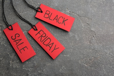 Red tags with words BLACK FRIDAY SALE on grey stone background, flat lay. Space for text