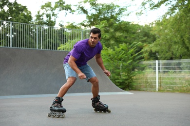 Photo of Handsome young man roller skating in park