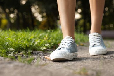 Woman in stylish shoes walking near green grass outdoors, closeup