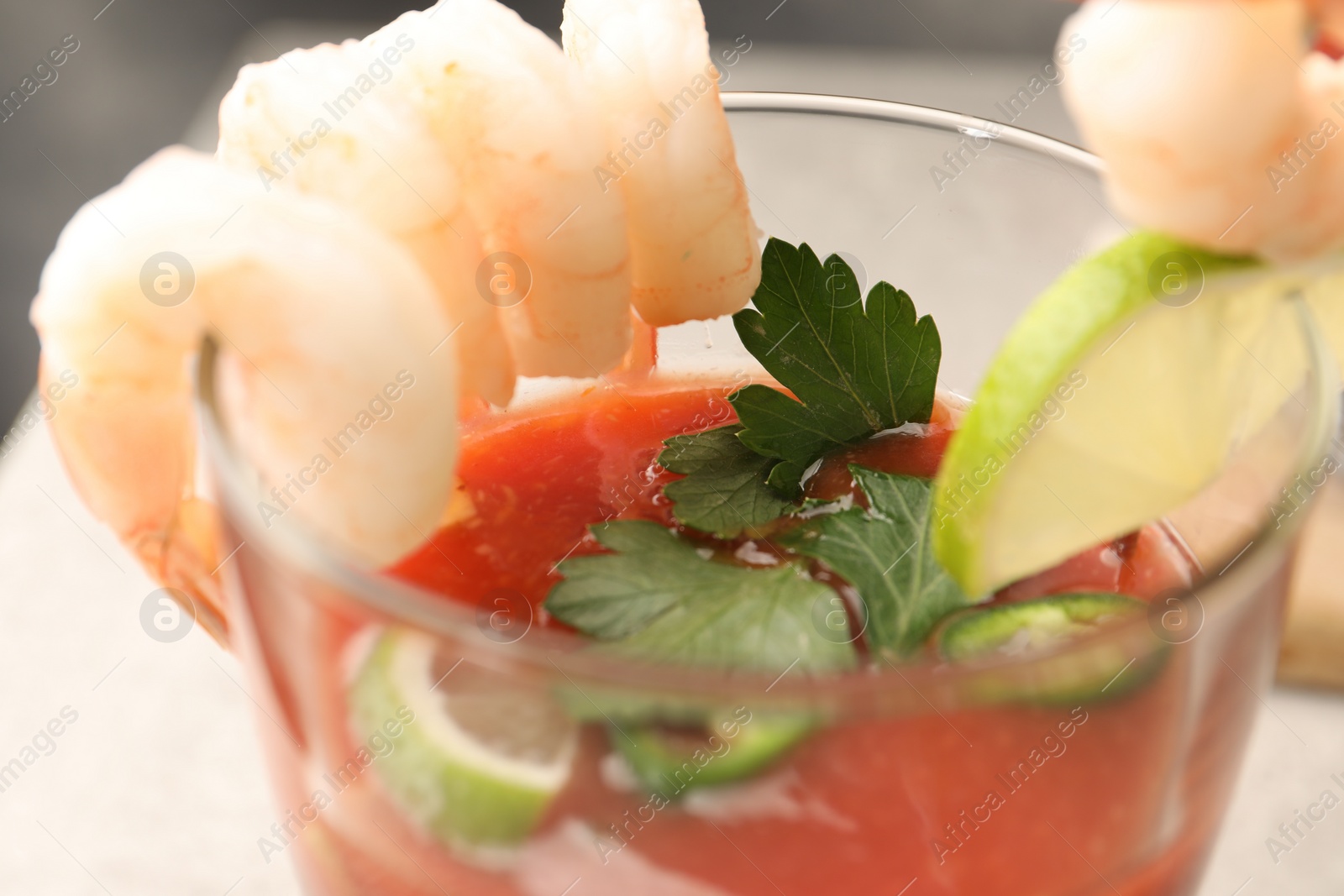 Photo of Tasty shrimp cocktail with sauce, parsley and lime in glass, closeup