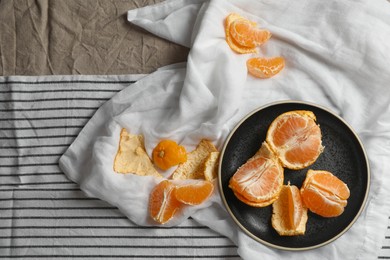 Photo of Fresh ripe tangerines on striped cloth, flat lay. Space for text
