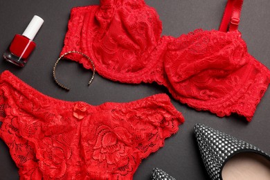 Composition with red women's underwear and shoes on dark grey background, closeup