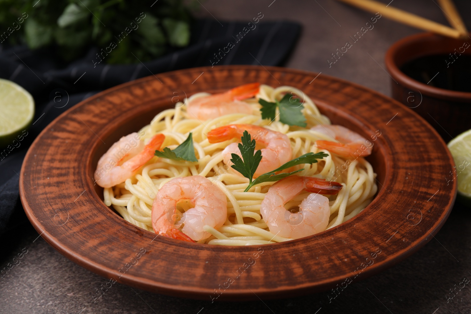 Photo of Tasty spaghetti with shrimps and parsley on brown table, closeup